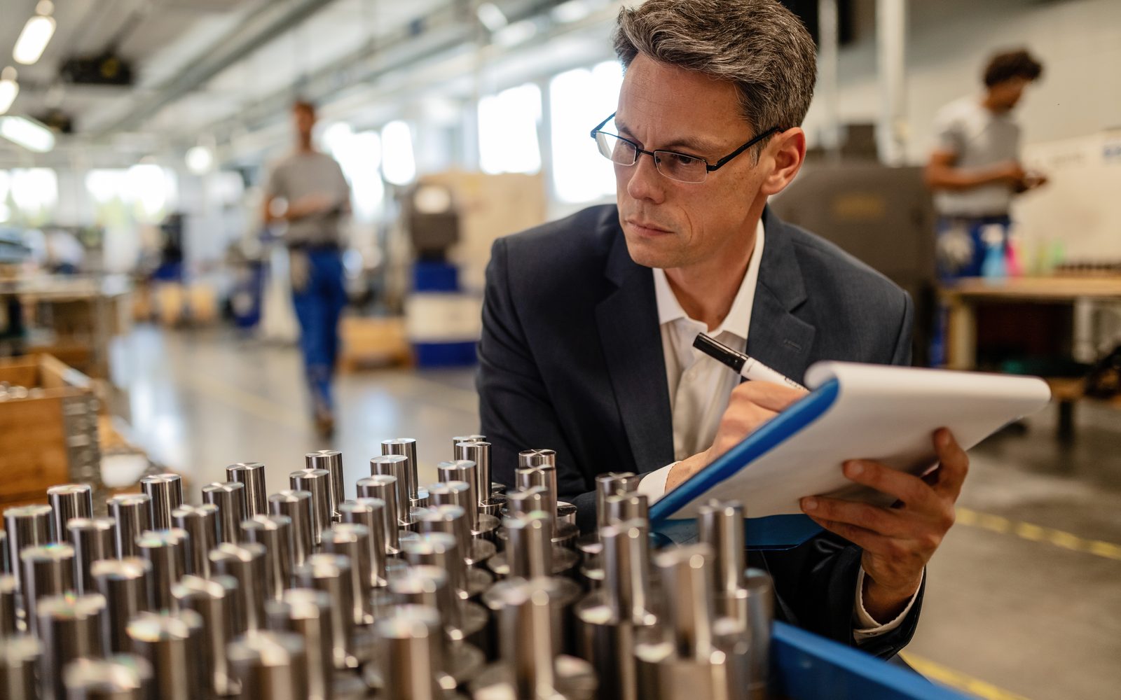 Quality inspector recording measurements against machined steel components